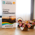 Na zdjęciu bukiety kwiatów w koszykach oraz roll-up Gminy Przemęt "Gmina szans i możliwości".