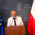 Na zdjęciu Mieczysław Jędrzychowski, były prezes Stowarzyszenia Gospodarczo-Edukacyjnego Przyjaciele Szkoły w Starkowie, który przemawia zza mównicy. W tle ścianka oraz flagi.