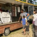 Uczestnicy wydarzenia zgromadzeni przy foodtrucku.