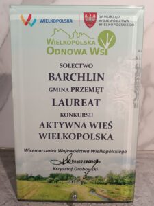 Na zdjęciu statuetka, na której widnieje logo WIELKOPOLSKA oraz herb Samorządu Województwa Wielkopolskiego. Treść: Wielkopolska Odnowa Wsi. Sołectwo Barchlin Gmina Przemęt Laureat konkursu Aktywna Wieś Wielkopolska. Wicemarszałek Województwa Wielkopolskiego Krzysztof Grabowski.