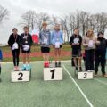 Na zdjęciu uczniowie na podium z dyplomami i medalami. Koło nich stoją nauczyciele.