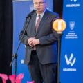Na fotografii marszałek, który stoi na scenie i przez mikrofon przemawia podczas uroczystości.