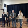 Na zdjęciu dyrektor szkoły Roman Smoczyk oraz wicedyrektorka szkoły ponadpodstawowej Joanna Kalitka, przemawiająca przez mikrofon. W tle widać dwójkę uczniów.