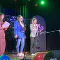 Na zdjęciu trzy przedszkolanki, które stoją na scenie i prowadzą wydarzenie.