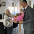 Na fotografii wójt wręcza jubilatce bukiet kwiatów.