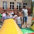 Na zdjęciu widać dzieci ustawione w kolejkę do dmuchanego zamku.