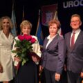 Na zdjęciu cztery osoby obecne na uroczystości, wśród nich burmistrz Śmigla. Jedna z kobiet trzyma bukiet róż.