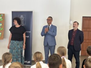 Na zdjęciu widoczny wójt, wicedyrektor szkoły oraz nauczycielka. W tle roll-up informujący o honorowym patronacie wójta.