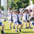 Zdjęcie przedstawia występ artystyczny grupy chłopców. Ubrani są w białe koszule i czarne krawaty.