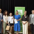 Wspólne zdjęcie, na którym są wójtowie, kierownik Placówki Terenowej KRUS, dyrektor GCKiB oraz laureatka, która pozuje z dyplomem i upominkami i dyrektorka szkoły z Kaszczoru.