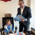 Na zdjęciu widoczna dziewczynka, która siedzi na fotelu wójta. Wójt trzyma w dłoni otrzymaną od niej laurkę.