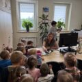 Na zdjęciu widoczne są dzieci w wydziale finansów. Z zainteresowaniem przyglądają się pracy księgowych.
