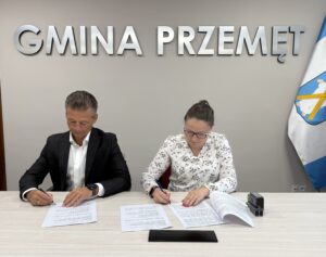 Na zdjęciu zastępca wójta oraz Katarzyna Mocek podczas podpisywania umowy. W tle srebrny napis "Gmina Przemęt".