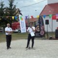 Na zdjęciu dwie osoby należące do OSP Kluczewo przemawiają podczas wydarzenia. W tle winder gminy Przemęt oraz winder OSP Kluczewo.