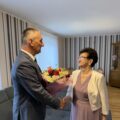Na zdjęciu uchwycono moment, gdy wójt wręcza jubilatce bukiet kwiatów i składa życzenia.
