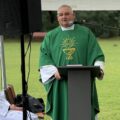 Na zdjęciu ksiądz podczas odprawiania mszy polowej. Na fotografii widoczny także ministrant.
