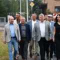 Na fotografii osoby uczestniczące w oficjalnym otwarciu drogi i ścieżki rowerowej. Na zdjęciu osoby te podążają wzdłuż ścieżki.