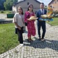 Na fotografii trzy osoby - dwie kobiety i jeden mężczyzna. Jedna z kobiet trzyma chleb, a mężczyzna koszyk, w którym znajdują się bułki.