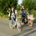 Na zdjęciu dwójka mężczyzn, którzy jadą na rowerach. Do jednego roweru została przyczepiona tabliczka z napisem "Barchlin dożynki 2025", rower ten został też ozdobiony kolorowymi wstążkami.