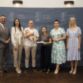Na zdjęciu uczestnicy gali noworodkowej. Na tle oficjalnej ścianki z herbem gminy stoją rodzice z niemowlęciem. Rodzice pozują z listem gratulacyjnym i upominkiem. Na fotografii Wójt Gminy Przemęt Janusz Frąckowiak, Przewodnicząca Rady Gminy Monika Maćkowiak, Zastępca Kierownika Urzędu Stanu Cywilnego Irena Mikołajczak i pracownik urzędu pani Natalia Chomska.