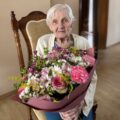Na zdjęciu pani Helena Skorupińska pozuje z dużym bukietem kwiatów.