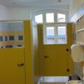 Wnętrze nowoczesnej łazienki w przedszkolu, z widocznymi kabinami sanitarnymi w kolorze żółtym oraz białymi umywalkami.