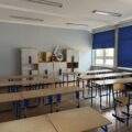 Na zdjęciu widoczna sala lekcyjna, w której znajdują się ławki z krzesłami oraz szafka.