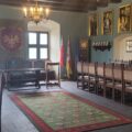 Na zdjęciu przedstawione jest jedno z pomieszczeń w Muzeum Opalińskich. Widać salę, w której znajdują się dwa duże stoły z krzesłami oraz biurko pośrodku. Na ścianach wiszą portrety ważnych postaci.