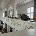 Zdjęcie wykonane zostało we wnętrzu odbudowanego kościoła poewangelickiego, który obecnie pełni funkcję biblioteki i muzeum. Na balkonie, w gablotach, można zobaczyć różnorodne eksponaty. Na zdjęciu widać zwiedzające osoby.