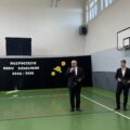 Na fotografii dyrektor Roman Smoczyk, który przemawia podczas rozpoczęcia roku szkolnego w Przemęcie na sali gimnastycznej. Obok niego stoi jeden z uczniów.
