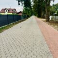 Na zdjęciu przedstawiono fragment wyremontowanej ulicy Starkowskiej. Po lewej stronie widoczne są ogrodzenia posesji, a po prawej drzewa. Jej główną, szarą część wykonano z kostki ażurowej, a obok niej przebiega czerwony pas z kostki brukowej, przeznaczony dla pieszych i rowerzystów.