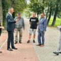 Na zdjęciu uczestnicy odbioru inwestycji stoją na drodze i prowadzą rozmowę.