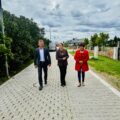 Na fotografii zastępca wójta gminy Przemęt Waldemar Kalitka, radna gminy Przemęt Kinga Piędel oraz sołtys Kaszczoru Beata Binkowska. Wyżej wymienione osoby idą nowo wybudowaną ulicą i rozmawiają o inwestycji.