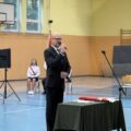 Na fotografii dyrektor Bartłomiej Górny, który przemawia podczas rozpoczęcia roku szkolnego w Buczu na sali gimnastycznej.