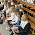 Na zdjęciu ukazani uczniowie, którzy siedzą na ławkach w sali gimnastycznej w Buczu podczas rozpoczęcia roku.