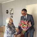 Na zdjęciu wójt przekazuje jubilatce bukiet kwiatów i składa jej życzenia urodzinowe.