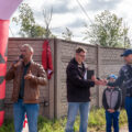 Na fotografii widoczny wójt, który przemawia przez mikrofon przed rozpoczęciem biegu. W tle m.in. konferansjer i prezes "Sokół" Włoszakowice.