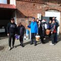 Na fotografii uczestnicy grzybobrania czekają w miejscu zbiórki. Zdjęcie wykonano przed wyprawą do lasu.