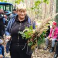 Na zdjęciu kobieta, która trzyma w ręce bukiet zrobiony z liści i innej roślinności.
