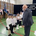 Na fotografii dyrektor szkoły pasuje pierwszoklasistów.