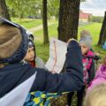 Grupa dzieci spogląda na mapę, którą trzyma chłopiec.