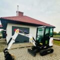Zdjęcie przedstawia nową, białą koparkę.