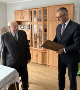 Na zdjęciu wójt, który odczytuje jubilatowi życzenia z listu gratulacyjnego.