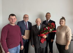 Na fotografii jubilat z bukietem kwiatów. Na zdjęciu także wójt, kierownik USC oraz rodzina jubilata.