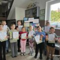 Grupowe zdjęcie uczniów, którzy wzięli udział w konkursie. Uczniowie pozują z dyplomami.