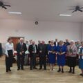 Grupowe zdjęcie seniorów z różami.
