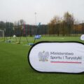 Na zdjęciu widoczny baner Ministerstwa Sportu i Turystyki, który został rozłożony na nowym boisku. W tle widać także rozstawione zestawy do badmintona.