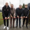 Na zdjęciu widoczni Minister Sportu i Turystyki Jakub Rutnicki, Starosta Powiatu Wolsztyńskiego Jacek Skrobisz, Wójt Gminy Przemęt Janusz Frąckowiak oraz uczeń ze szkoły. Wszystkie te osoby przecinają czerwoną wstęgę, co symbolizuje oficjalne otwarcie.