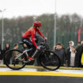 Na zdjęciu widoczna kobieta podczas pokazowego przejazdu po pumptracku. W tle widoczni uczniowie oglądający inauguracyjny przejazd.
