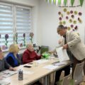 Na zdjęciu widoczny wójt, który rozdaje odblaskowe kamizelki seniorom.